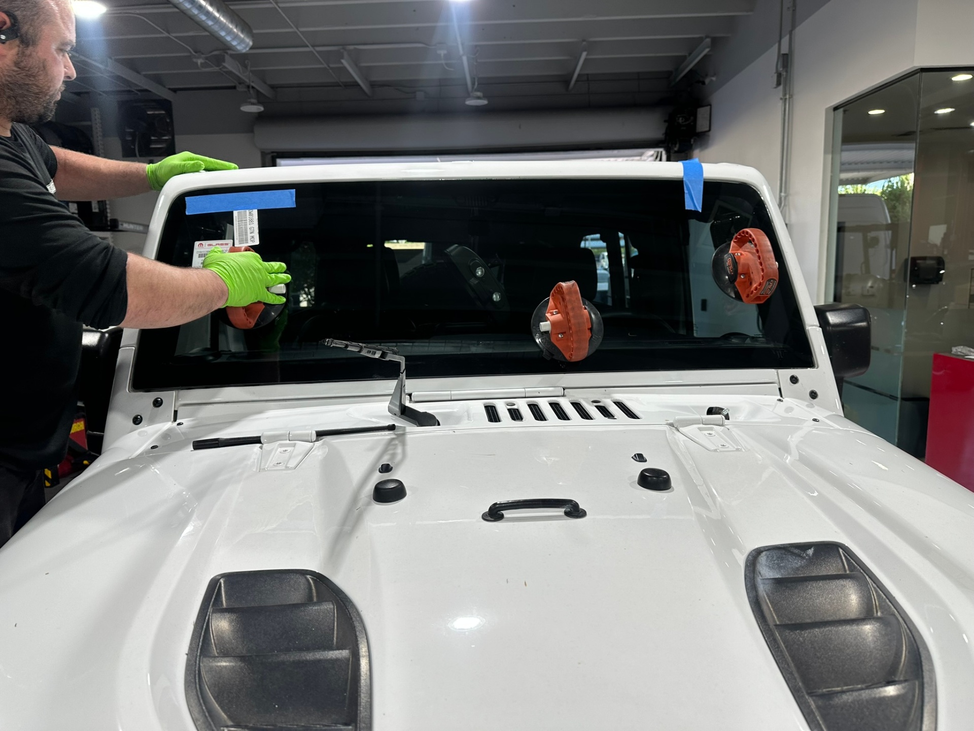 Professional windshield protection film installation on a white Jeep